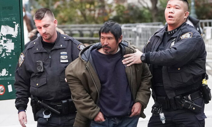 Craig Tamanaha, who was later charged with setting fire to a Christmas tree outside the Fox News headquarters, is detained by police after exposing himself outside the court at the trial of Ghislaine Maxwell in the Manhattan borough of N.Y.C., on Nov. 29, 2021. (Carlo Allegri/Reuters)