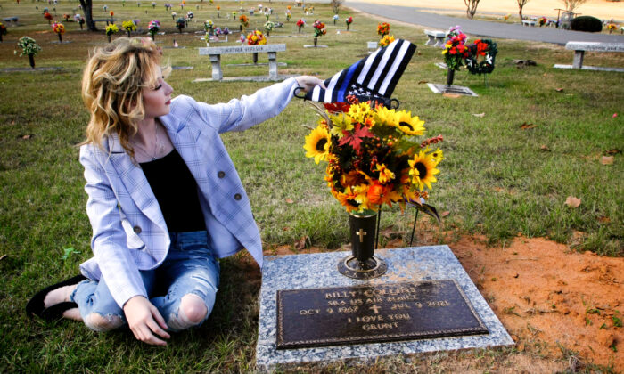 Danielle Collins, daughter of slain police officer William "Billy" Collins, adjusts a flag at her father's gravestone in Doyline, La., on Nov. 17, 2021. She said she visits his gravestone on occasion, especially when she has a " a bad day." (Bobby Sanchez for The Epoch Times)