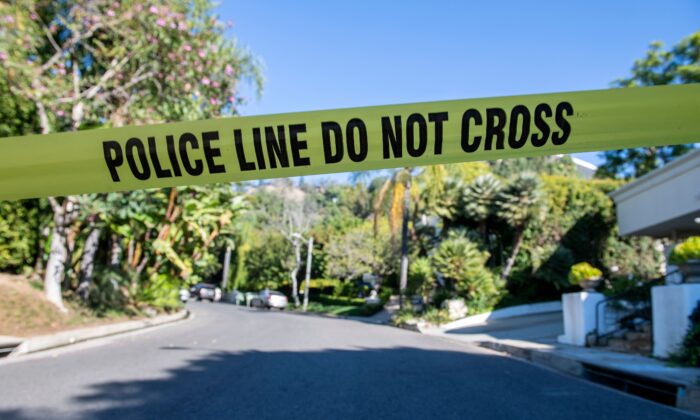 A yellow police tape blocks access to the scene of a burglary and shooting in Beverly Hills, Calif., on Dec. 1, 2021.  (Valerie Macon/AFP via Getty Images)