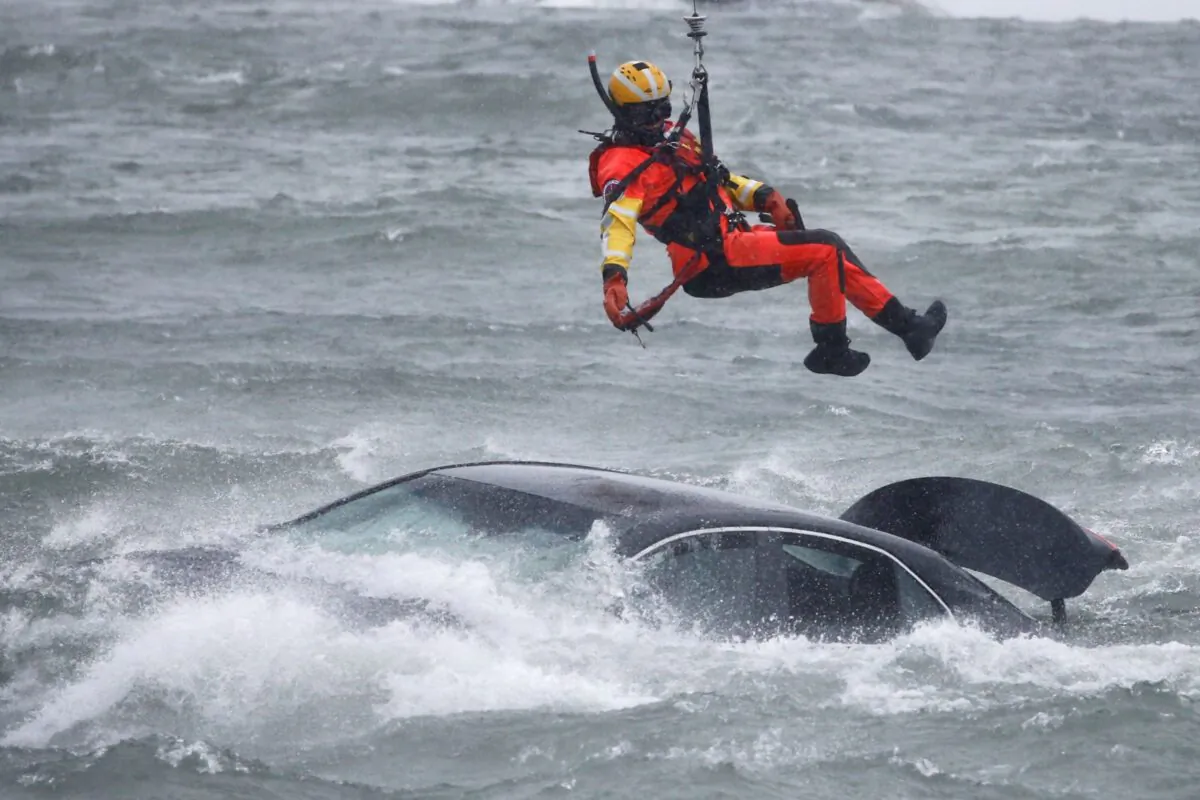 A U.S. Coast Guard diver is lowered from a hovering helicopter to pull a body from a submerged vehicle stuck in rushing rapids just yards from the brink of Niagara Falls, in Niagara Falls, N.Y., on Dec. 8, 2021. (Jeffrey T. Barnes/AP Photo)