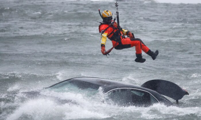 A U.S. Coast Guard diver is lowered from a hovering helicopter to pull a body from a submerged vehicle stuck in rushing rapids just yards from the brink of Niagara Falls, in Niagara Falls, N.Y., on Dec. 8, 2021. (Jeffrey T. Barnes/AP Photo)