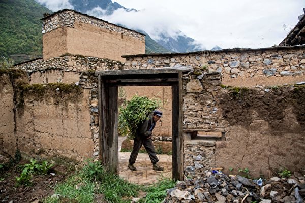 A villager carrying food for his livestock passes devastated houses in the old village of Luobozhai (Radish Village), which was damaged during the 2008 Sichuan earthquake, in Wenchuan county, Sichuan Province, on April 23, 2018.  (Johannes Eisele/AFP via Getty Images)