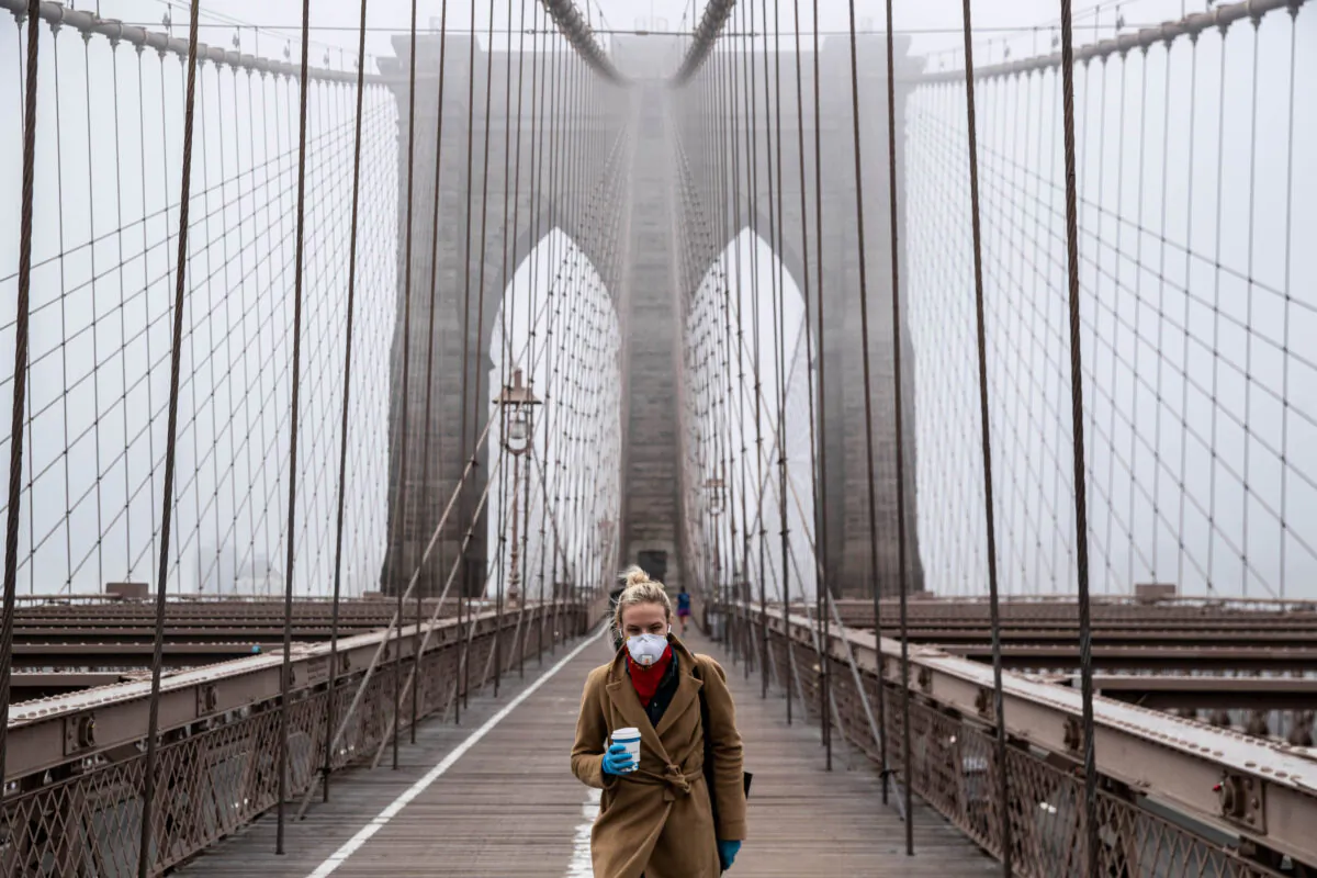 A woman wearing a mask walks the Brooklyn Bridge in the midst of the COVID-19 outbreak in New York City on March 20, 2020. (Victor J. Blue/Getty Images)