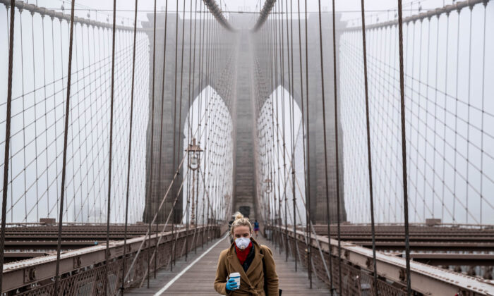 A woman wearing a mask walks the Brooklyn Bridge in the midst of the COVID-19 outbreak in New York City on March 20, 2020. (Victor J. Blue/Getty Images)