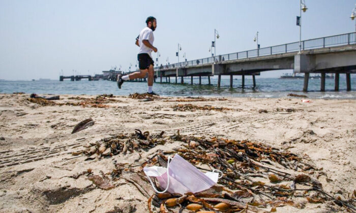 A man runs next to a discarded mask at the Belmont Veterans Memorial Pier in Long Beach, Calif., on Aug. 22, 2020. (Apu Gomes/AFP via Getty Images)