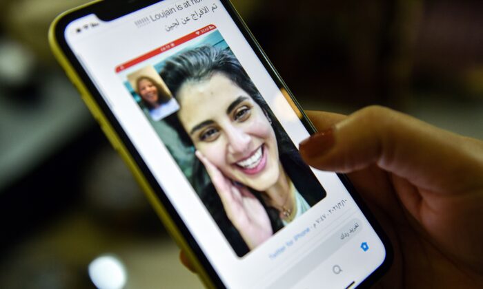 This picture taken Feb. 10, 2021 in Saudi Arabia's capital Riyadh shows a woman viewing a tweet posted by the sister of Saudi activist Loujain al-Hathloul, Lina, showing a screenshot of them having a video call following Hathloul's release after nearly three years in detention. Saudi authorities on February 10 released the prominent women's rights activist, her family said. (Fayez Nureldine/AFP via Getty Images)