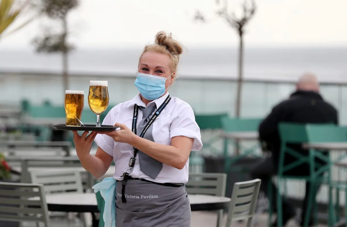 A waitress delivering beer with a mask on in an undated file photo. (Gareth Fuller/PA)