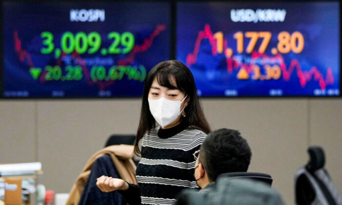 Currency traders talk each other near screens showing the Korea Composite Stock Price Index (KOSPI) (L), and the foreign exchange rate between U.S. dollar and South Korean won (R) at the foreign exchange dealing room of the KEB Hana Bank headquarters in Seoul, South Korea, on Dec. 10, 2021. (Ahn Young-joon/AP Photo)