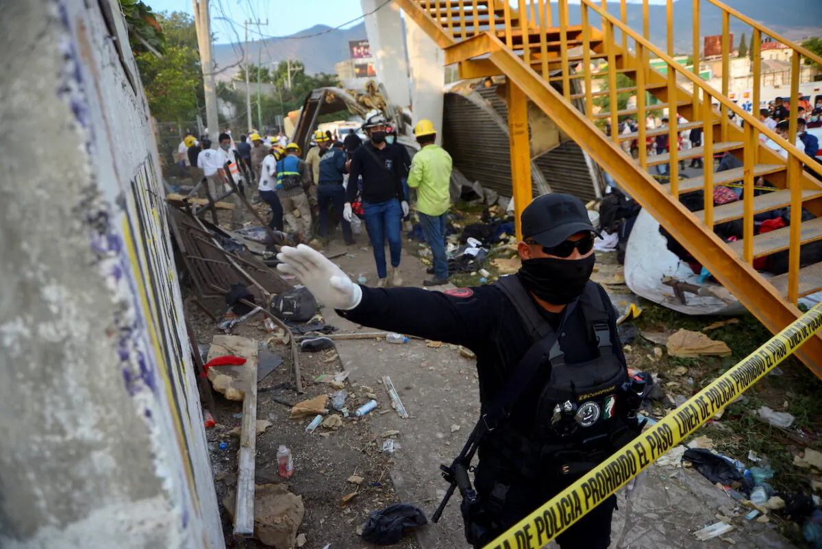 A police officer raises his arm to block photographers to to avoid taking pictures at the site of a trailer accident that left at least 49 people dead, most of them migrants from Central America, in Tuxtla Gutierrez, in Chiapas state, Mexico, on Dec. 9, 2021. (Jacob Garcia/Reuters)