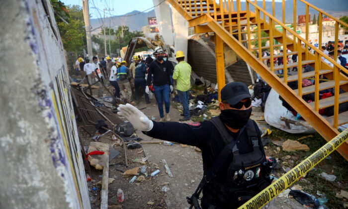 A police officer raises his arm to block photographers to to avoid taking pictures at the site of a trailer accident that left at least 49 people dead, most of them migrants from Central America, in Tuxtla Gutierrez, in Chiapas state, Mexico, on Dec. 9, 2021. (Jacob Garcia/Reuters)