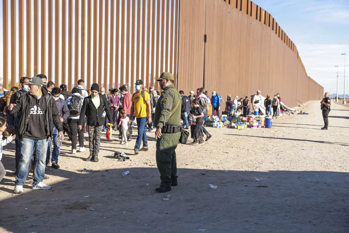 A Border Patrol agent organizes illegal immigrants who have gathered by the border fence after crossing from Mexico into the United States in Yuma, Arizona, on Dec. 10, 2021. (Charlotte Cuthbertson/The Epoch Times)