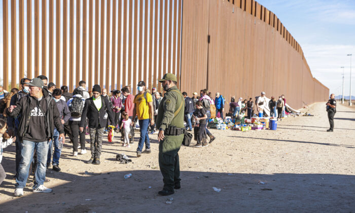 一名边境巡逻人员于 2021 年 12 月 10 日在亚利桑那州尤马市组织从墨西哥进入美国后聚集在边境围栏旁的非法移民。（夏洛特·卡斯伯森/纳闻时报）