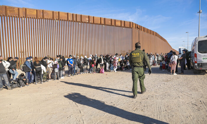 A Border Patrol agent organizes illegal immigrants who have gathered by the border fence after crossing from Mexico into the United States in Yuma, Arizona, on Dec. 10 2021. (Charlotte Cuthbertson/The Epoch Times)