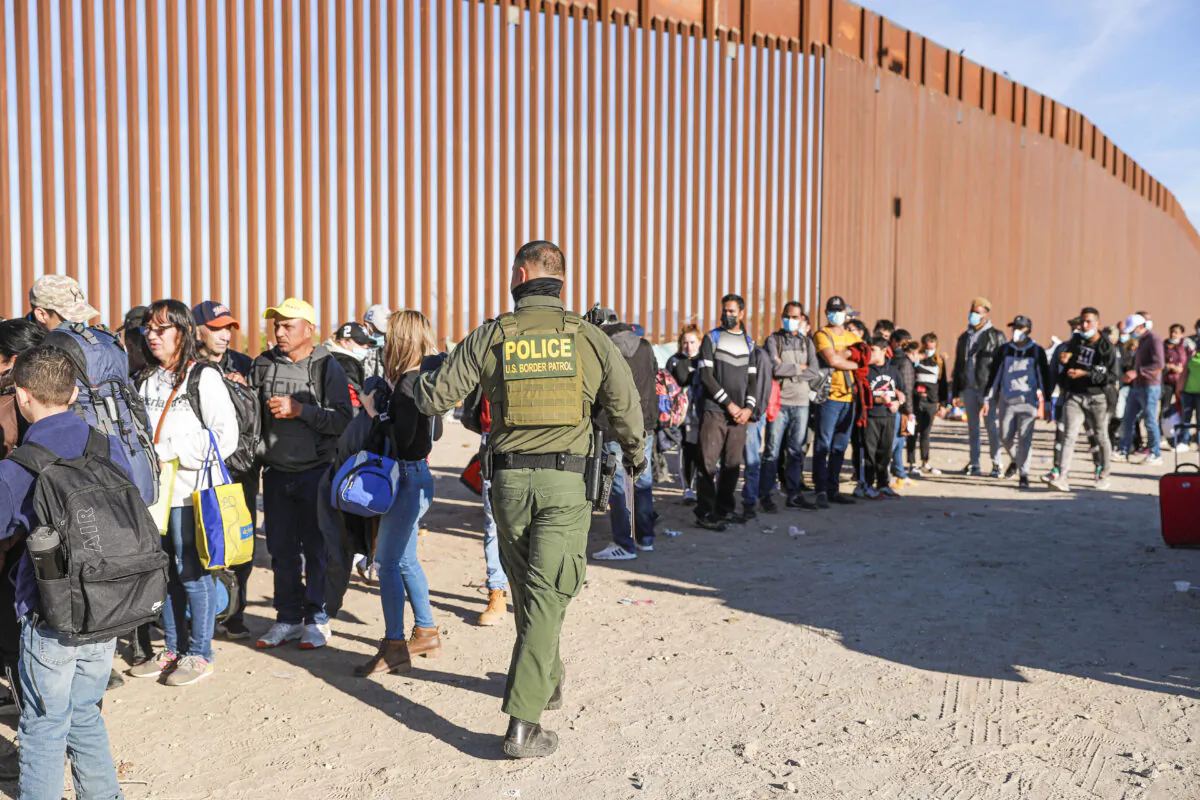 A Border Patrol agent organizes illegal immigrants who have gathered by the border fence after crossing from Mexico into the United States in Yuma, Ariz., on Dec. 10, 2021. (Charlotte Cuthbertson/The Epoch Times)