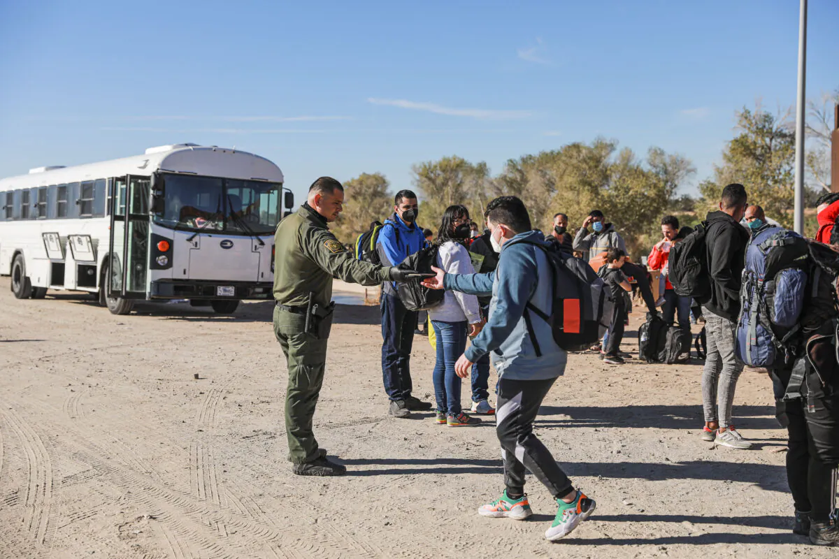 A Border Patrol agent organizes illegal immigrants who have gathered by the border fence after crossing from Mexico into the United States in Yuma, Ariz., on Dec. 10 2021. (Charlotte Cuthbertson/The Epoch Times)