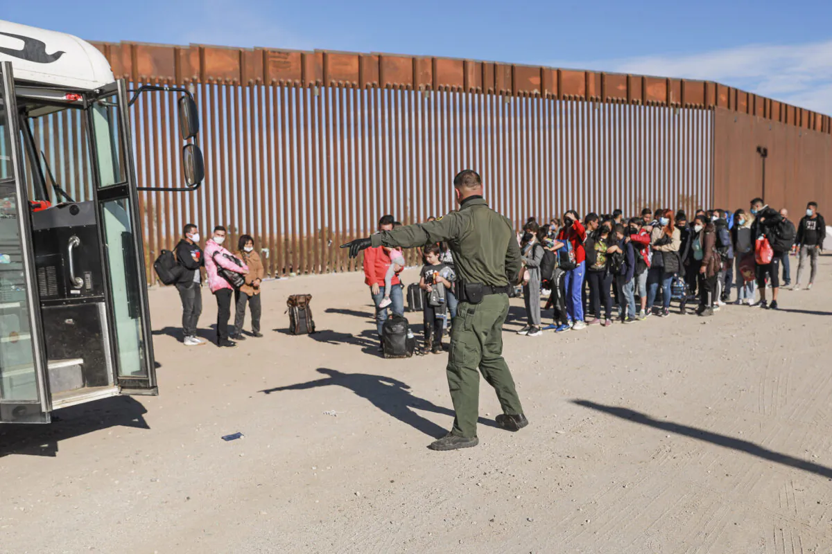 A Border Patrol agent organizes illegal immigrants who have gathered by the border fence after crossing from Mexico into the United States in Yuma, Ariz., on Dec. 10 2021. (Charlotte Cuthbertson/The Epoch Times)