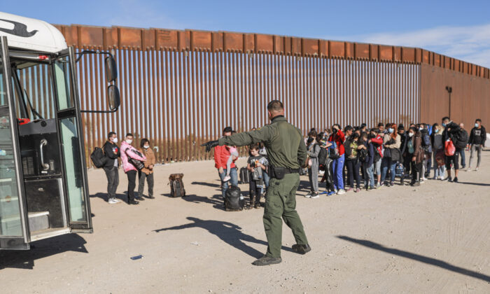 A Border Patrol agent organizes illegal immigrants who have gathered by the border fence after crossing from Mexico into the United States in Yuma, Arizona, on Dec. 10 2021. (Charlotte Cuthbertson/  Pezou)