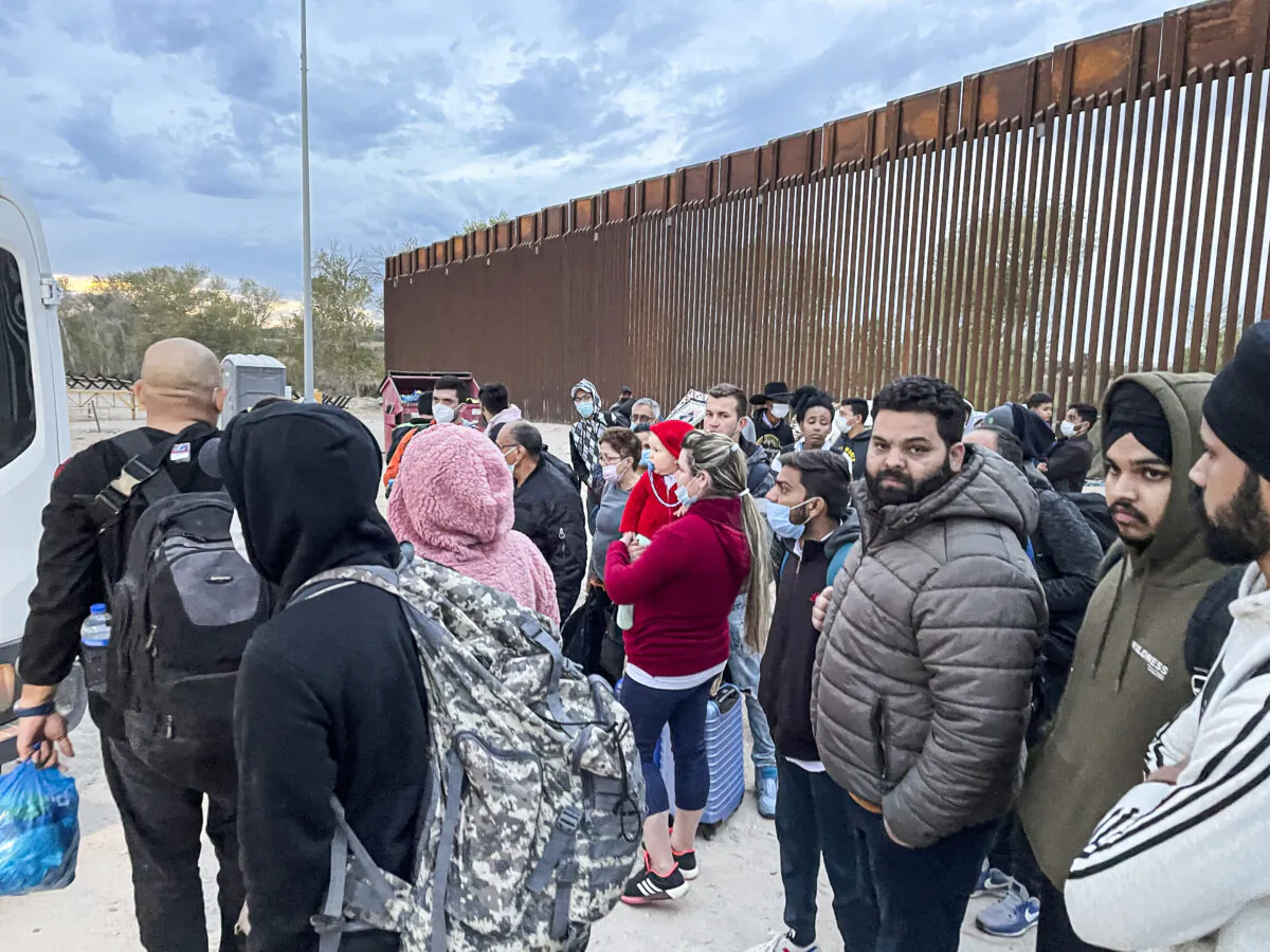 Illegal immigrants gather by the border fence after crossing from Mexico into the United States in Yuma, Ariz., on Dec. 9, 2021. (Charlotte Cuthbertson/The Epoch Times)