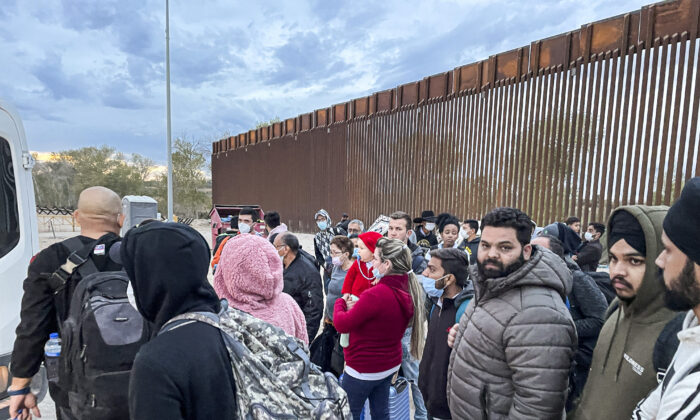 Illegal immigrants gather by the border fence after crossing from Mexico into the United States in Yuma, Ariz., on Dec. 9, 2021. (Charlotte Cuthbertson/The Epoch Times)