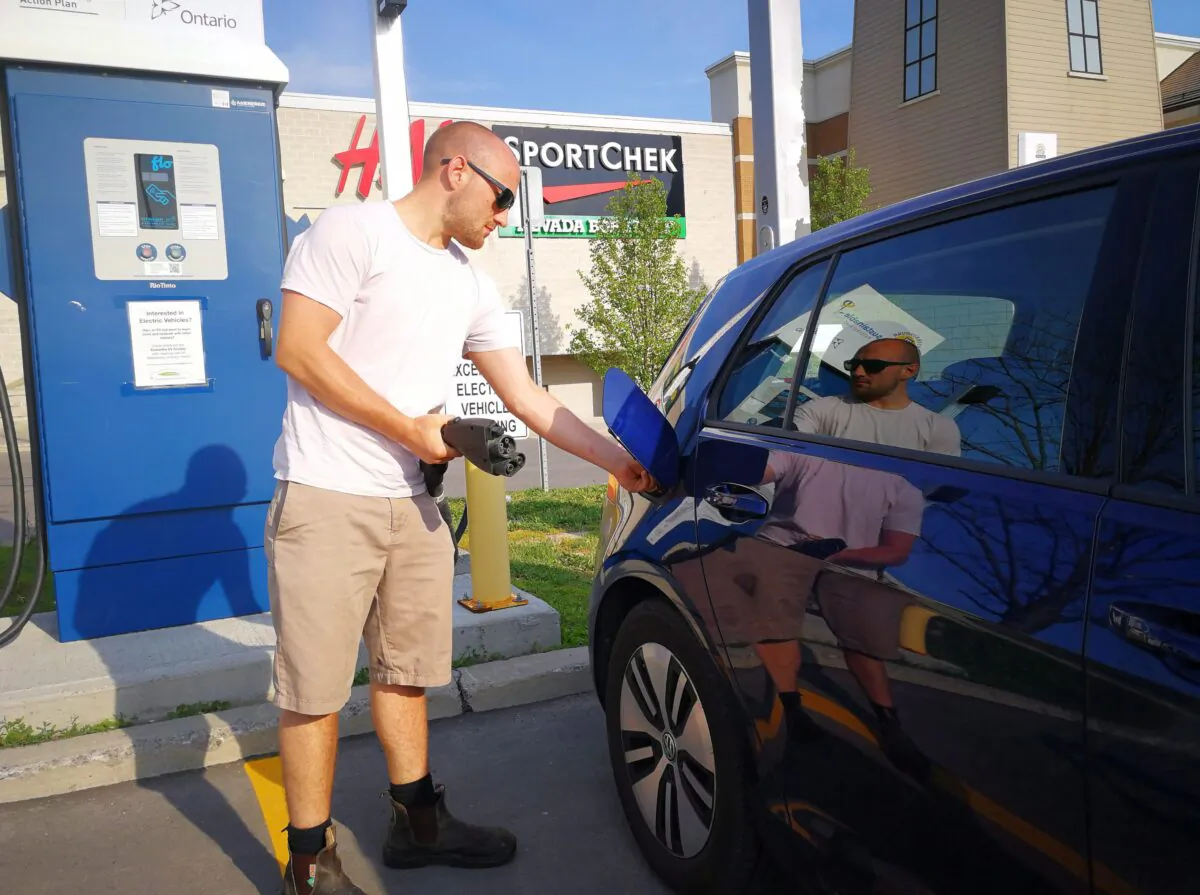A man plugs in his electric car at a charging station at Lansdowne Mall in Peterborough, Ont., on June 17, 2018. (The Canadian Press/Doug Ives)