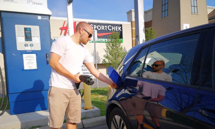 A man plugs in his electric car at a charging station at Lansdowne Mall in Peterborough, Ont., on June 17, 2018. (The Canadian Press/Doug Ives)