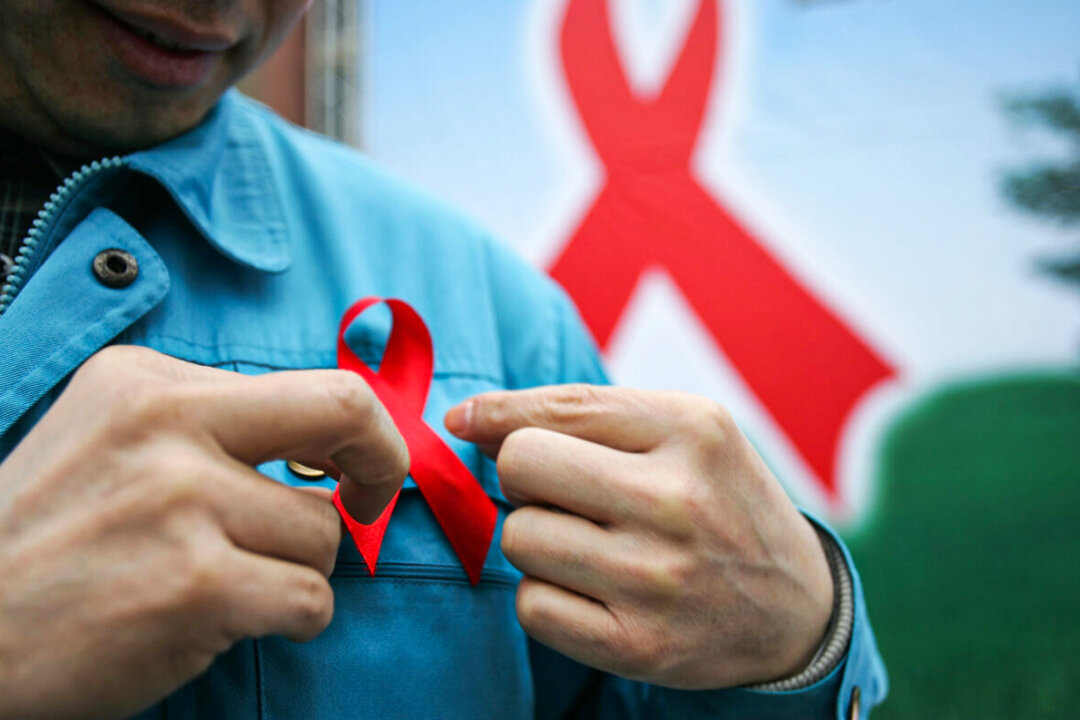 A migrant worker wears a red ribbon during an event organized by the local government to promote HIV/AIDS knowledge among migrant workers in Chengdu, Sichuan Province, southwest China, on Dec. 1, 2005. (China Photos/Getty Images)