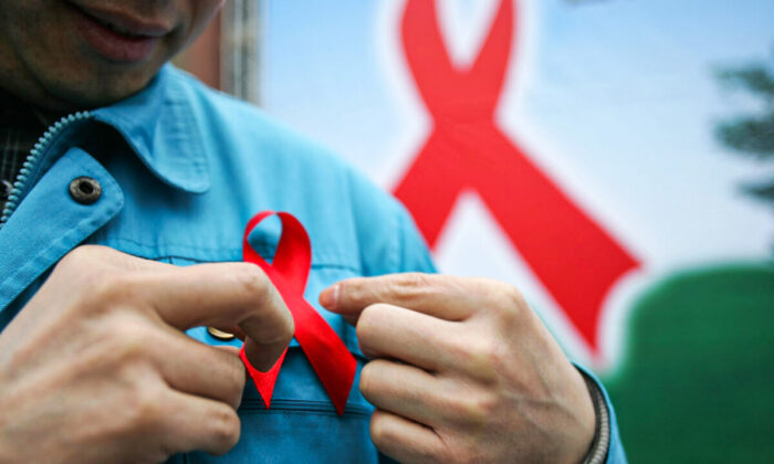 A migrant worker wears a red ribbon during an event organized by the local government to promote HIV/AIDS knowledge among migrant workers in Chengdu, Sichuan Province, southwest China, on Dec. 1, 2005. (China Photos/Getty Images)