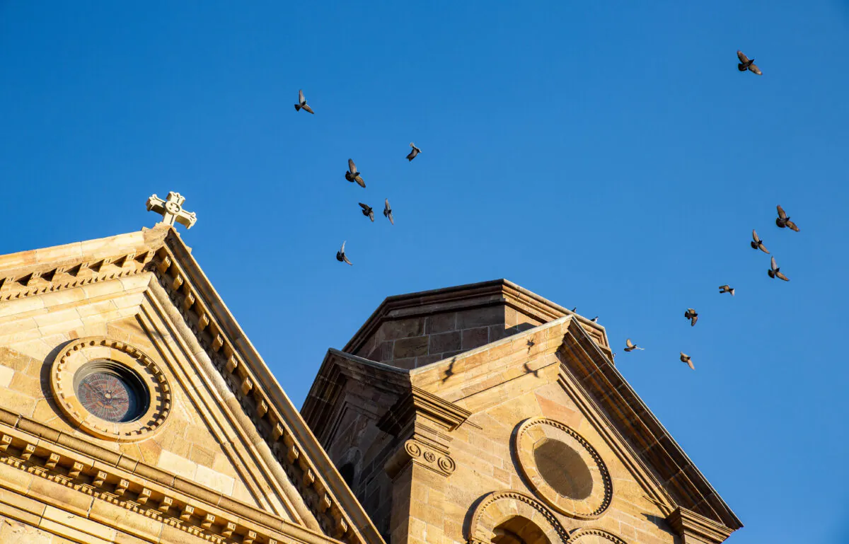 Birds fly over a Catholic Church in Santa Fe, New Mexico, on Dec. 4, 2021. (John Fredricks/The Epoch Times)