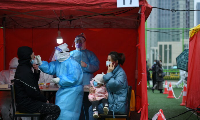 A medical worker in protective suit collects a swab from a man at a makeshift nucleic acid testing site inside a sports center in Binhai New Area, in Tianjin, China, on Nov. 21, 2020. (cnsphoto via Reuters)