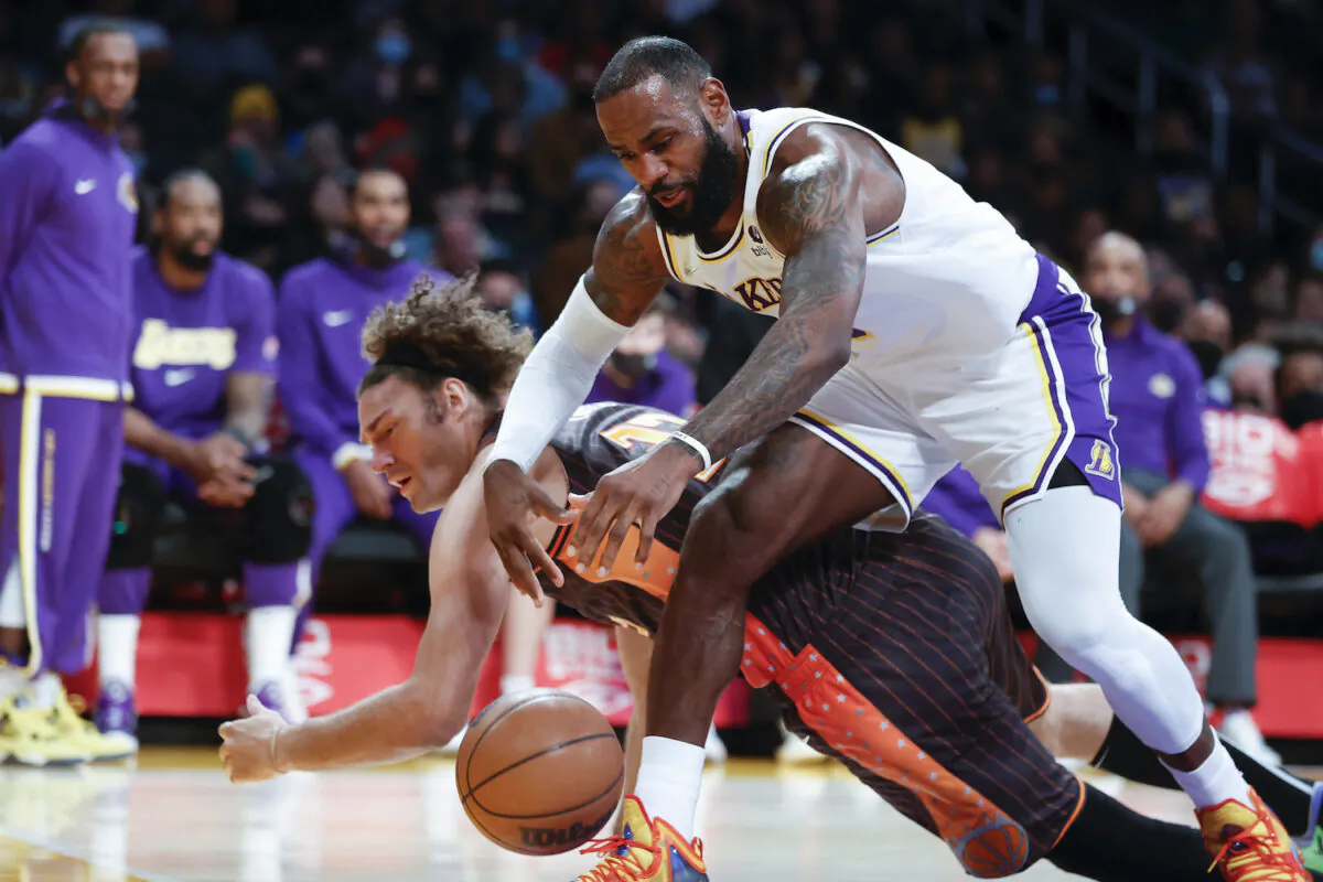 Los Angeles Lakers forward LeBron James, front, fights for a ball against Orlando Magic center Robin Lopez during the first half of an NBA basketball game in Los Angeles on Dec. 12, 2021. (AP Photo/Ringo H.W. Chiu)
