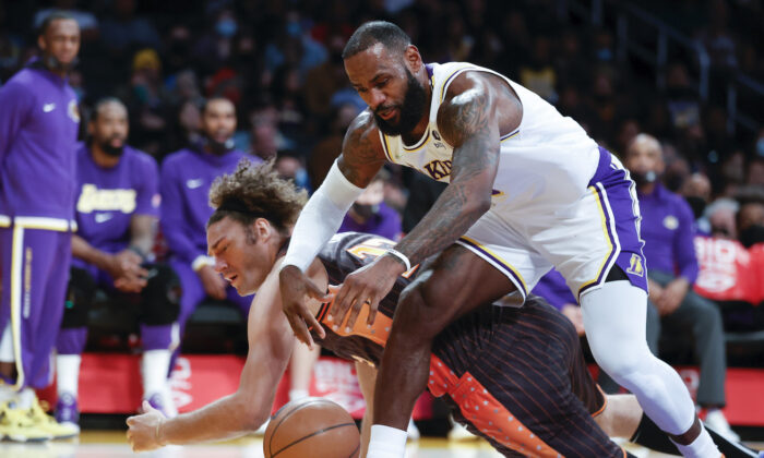 Los Angeles Lakers forward LeBron James, front, fights for a ball against Orlando Magic center Robin Lopez during the first half of an NBA basketball game in Los Angeles on Dec. 12, 2021. (AP Photo/Ringo H.W. Chiu)