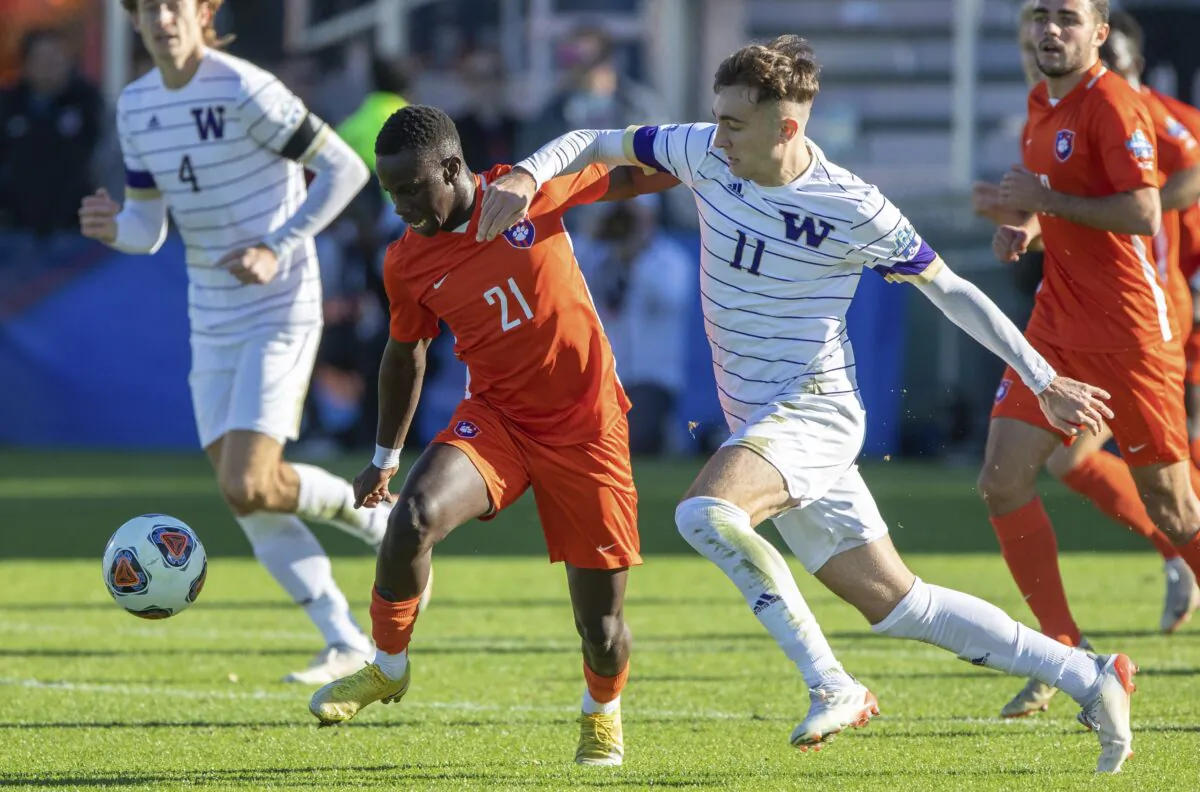 Clemson's Ousmane Sylla (21) and Washington's Nick Scardina (11) battle for a ball during the NCAA game in Cary, N.C., on Dec. 12, 2021. (Ben McKeown/AP Photo)