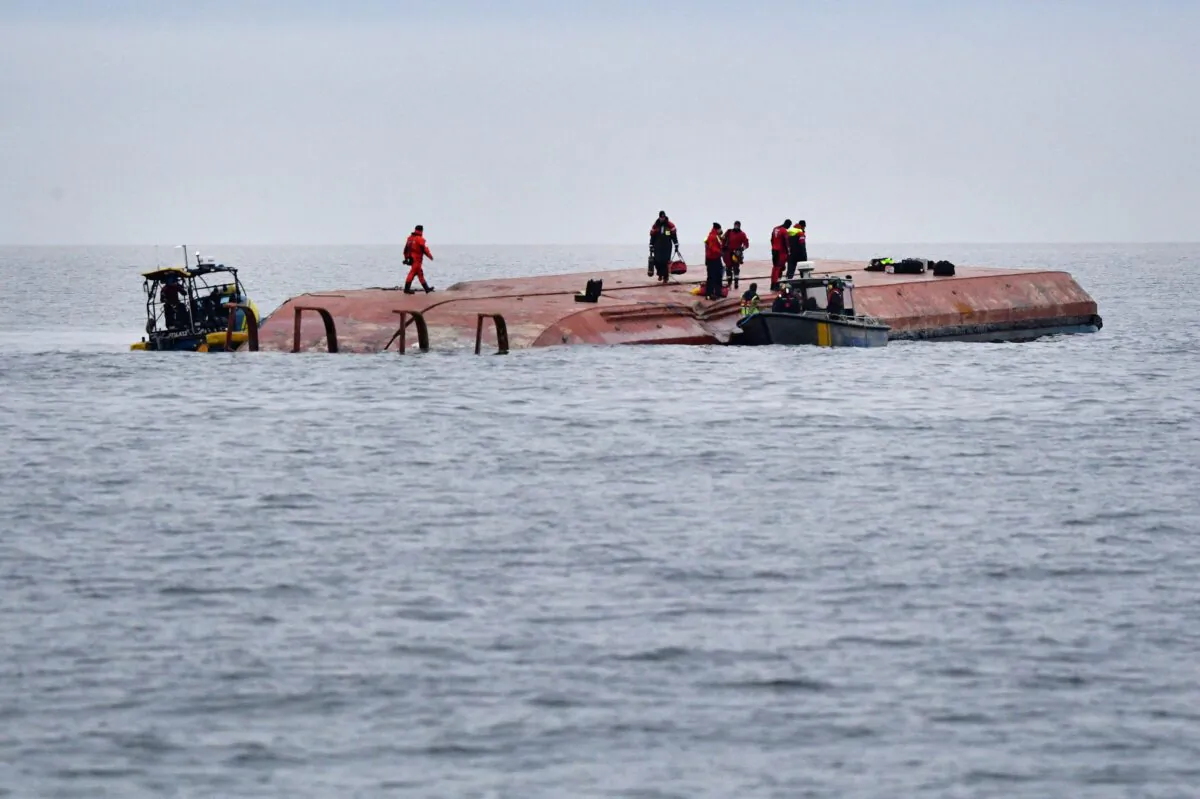 Divers work aboard the Danish cargo ship Karin Hoej, which collided with the British cargo ship Scot Carrier, between Ystad and Bornholm, on the Baltic Sea, on Dec. 13, 2021. (Johan Nilsson/TT News Agency via Reuters)