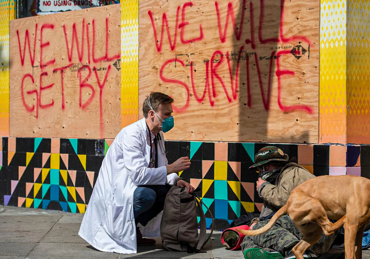 Stuart Malcolm, a doctor with the Haight Ashbury Free Clinic, speaks with homeless people in the Haight Ashbury area of San Francisco, Calif. on Mar. 17, 2020. (Josh Edelson/AFP via Getty Images)