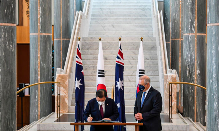 Australian Prime Minister Scott Morrison (R) looks on as South Korean President Moon Jae-in signs the official visitors book at Parliament House on December 13, 2021 in Canberra, Australia.   (Lukas Coch - Pool/Getty Images)