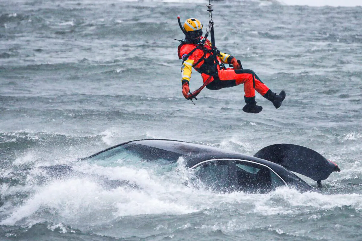 A U.S. Coast Guard diver is lowered from a hovering helicopter to pull a body from a submerged vehicle stuck in rushing rapids just yards from the brink of Niagara Falls, in Niagara Falls, N.Y., on Dec. 8, 2021. (Jeffrey T. Barnes/AP Photo)