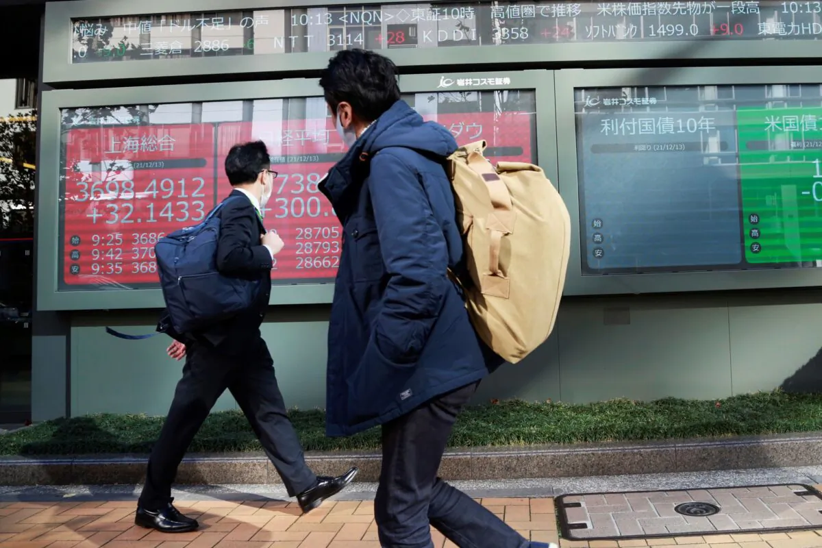 People walk by an electronic stock board of a securities firm in Tokyo, Japan, on Dec. 13, 2021. (Koji Sasahara/AP Photo)