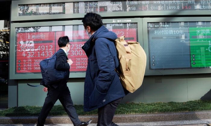 People walk by an electronic stock board of a securities firm in Tokyo, Japan, on Dec. 13, 2021. (Koji Sasahara/AP Photo)