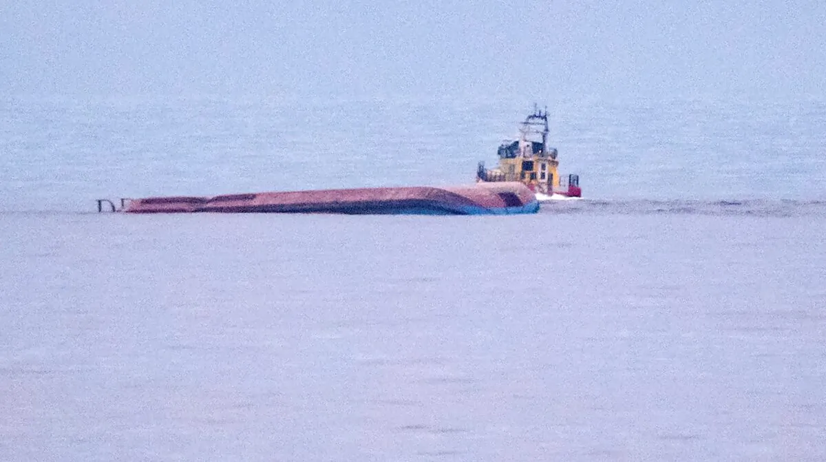 A rescue boat navigates by the capsized Danish cargo ship Karin Hoej after it collided with British cargo vessel Scot Carrier in the Baltic Sea, between Ystad and Bornholm, early on Dec. 13, 2021. (Johan Nilsson/TT via AP)