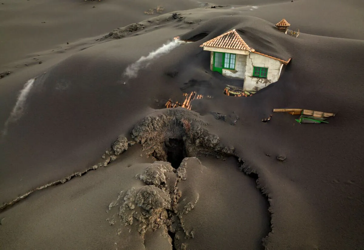A fissure is seen next to a house covered with ash on the Canary island of La Palma, Spain, on Dec. 1, 2021. (Emilio
Morenatti/AP Photo)