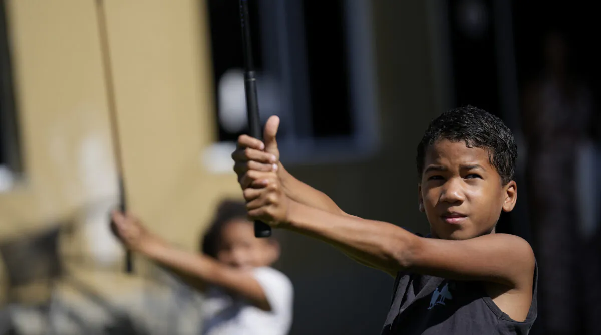 Children learn the basics of golf from caddie Marcelo Modesto, on the grounds of the Nusacquilombo cultural center in Cidade de Deus or City of God favela, in Rio de Janeiro, Brazil, on Dec. 9, 2021. (Silvia Izquierdo/AP Photo)