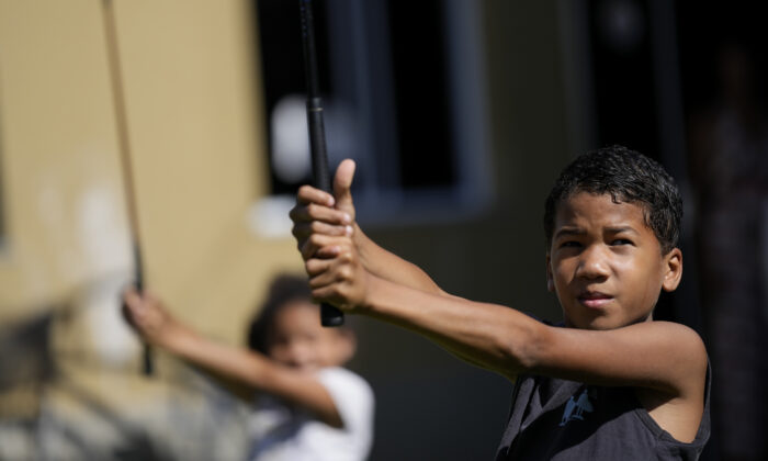Children learn the basics of golf from caddie Marcelo Modesto, on the grounds of the Nusacquilombo cultural center in Cidade de Deus or City of God favela, in Rio de Janeiro, Brazil, on Dec. 9, 2021. (Silvia Izquierdo/AP Photo)