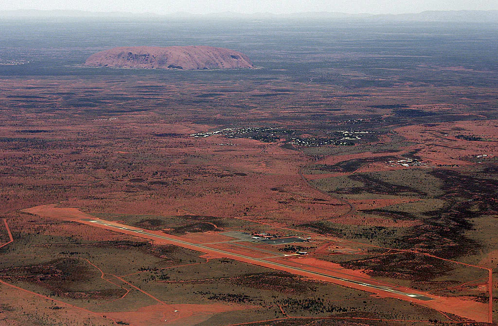 The resort town of Yulara (C) and Connellan Airport (front) lie before the arkose massif of Uluru (Ayers Rock) rising 348 metres above the surrounding desert of central Australia, 17 February 2007(TORSTEN BLACKWOOD/AFP via Getty Images)