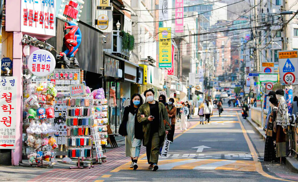 A couple wearing masks to protect against contracting the COVID-19 walk along a street in Seoul, South Korea, on April 3, 2020. (Heo Ran/Reuters)