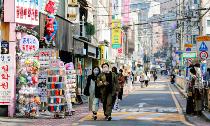 A couple wearing masks walk along a street in Seoul, South Korea, on April 3, 2020. (Heo Ran/Reuters)
