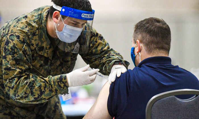 A member of the U.S. Armed Forces administers a COVID-19 vaccine to a police officer at a FEMA community vaccination center in Philadelphia, Pa., on March 2, 2021. (Mark Makela/Getty Images)