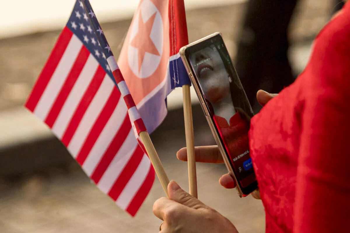 A woman holds American and North Korean flags as she walks along Sword Lake in Hanoi, Vietnam, on Feb. 27, 2019. (Andrew Harnik/AP Photo)