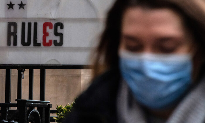 Commuters wearing face masks walk past a sign outside a bar in the city of London on Dec. 9, 2021. (Chris J Ratcliffe/Getty Images)