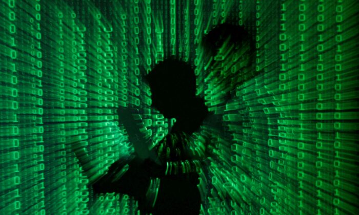 An illustration picture shows a projection of binary code on a man holding a laptop computer. (Kacper Pempel/Reuters)
