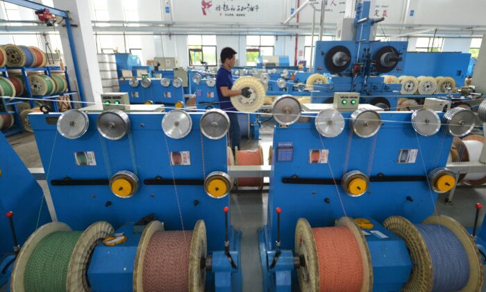 An employee works at a production line manufacturing optical fiber cables at a factory of the Zhejiang Headway Communication Equipment Co. in Huzhou, Zhejiang Province, China, on May 15, 2019. (Stringer/Reuters)